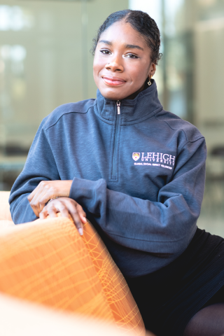 Nahjiah Miller poses for a photo sitting on a chair and smiling at the camera